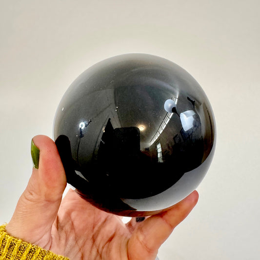Large black obsidian crystal ball from FoxlarkCrystals, showcasing smooth, polished black obsidian with natural reflective surface.