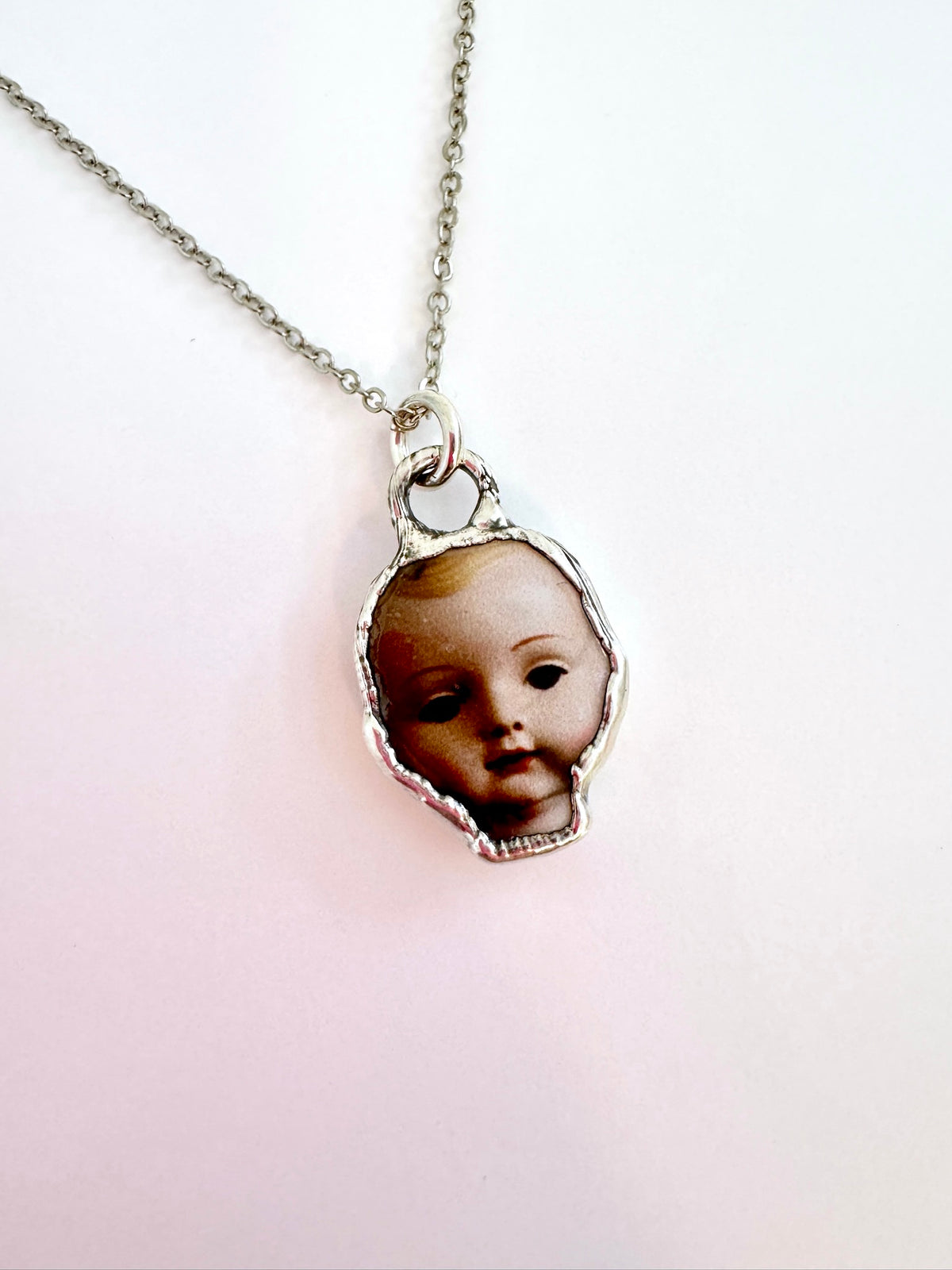 Doll head pendant necklace in fine silver from FOXLARK's Weirdlings Collection, featuring a detailed doll head design.
