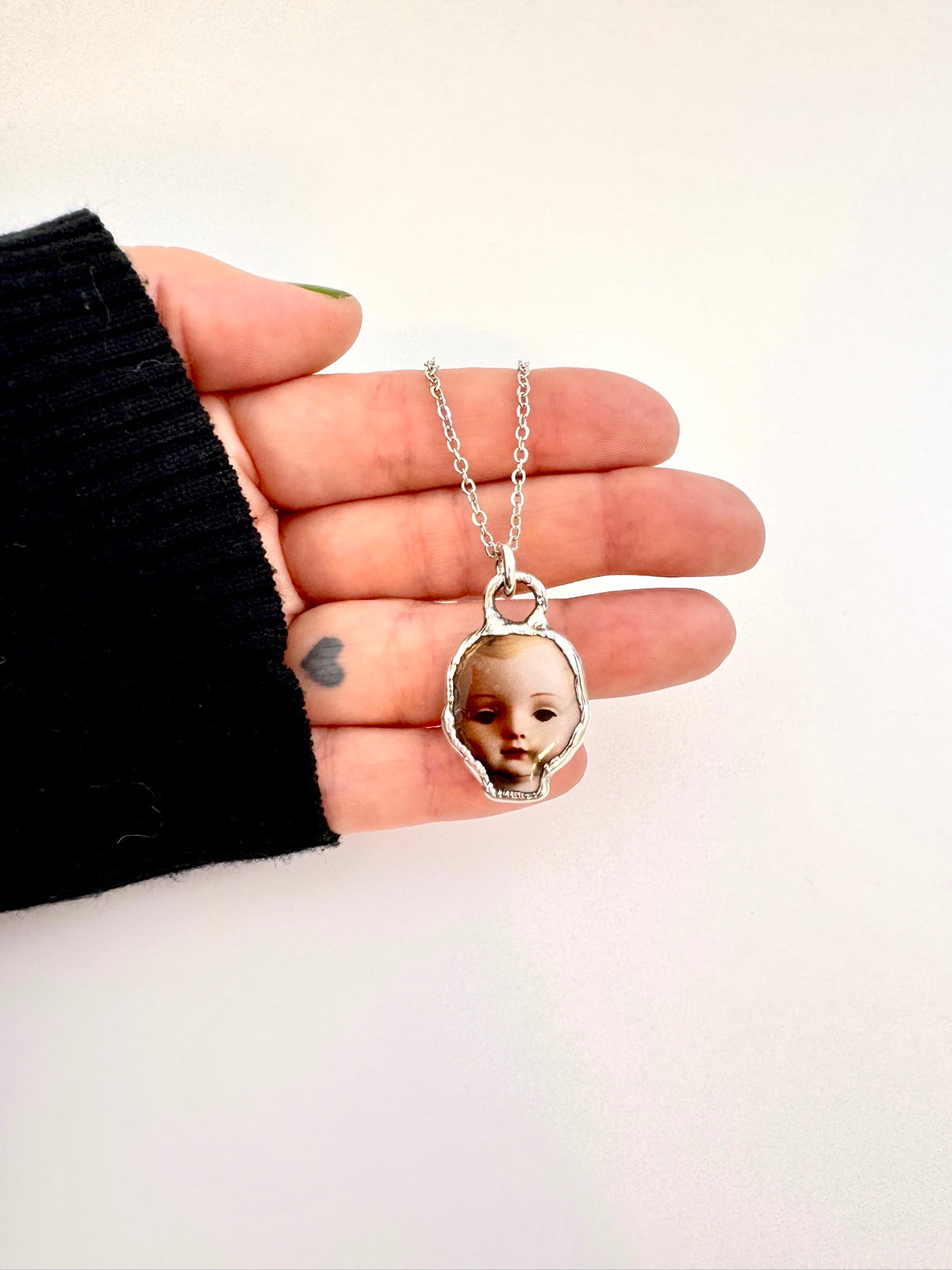 Silver doll head necklace from FOXLARK's Weirdlings Collection, featuring a detailed fine silver doll head pendant.