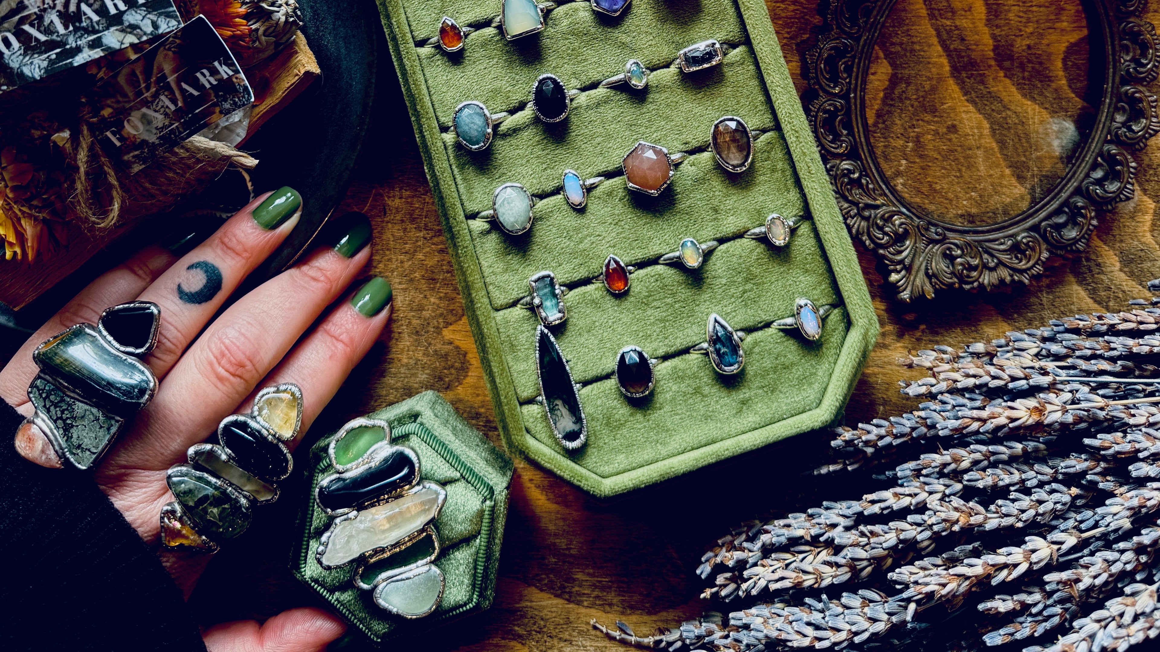 Large Crystal Jewelry display with rings on a green tray, surrounded by crystals and sage on a wooden surface.